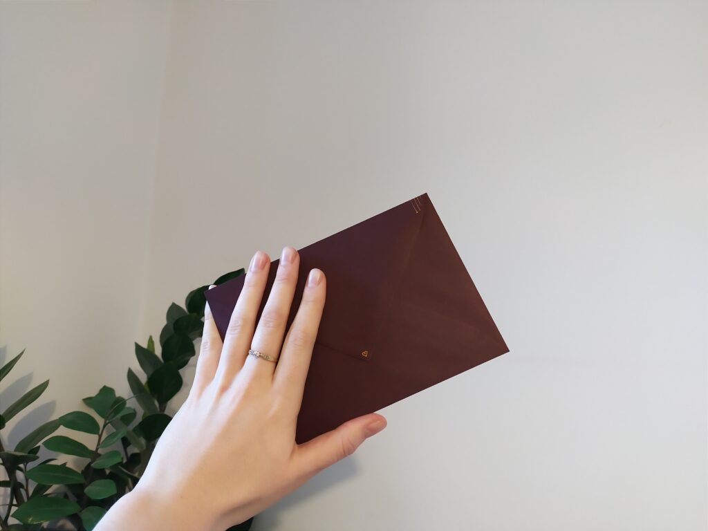 ciemnoczerwona koperta z listem trzymana w ręce 
